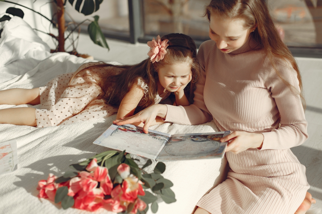 cheerful-mother-and-daughter-reading-book-on-bed-3875332.jpg